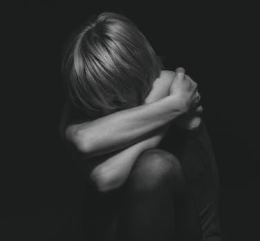 Grayscale Photo of a Person Hugging Self